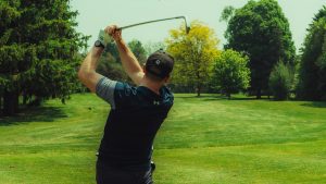 Golfeur qui swingue sur un parcours de golf verdoyant