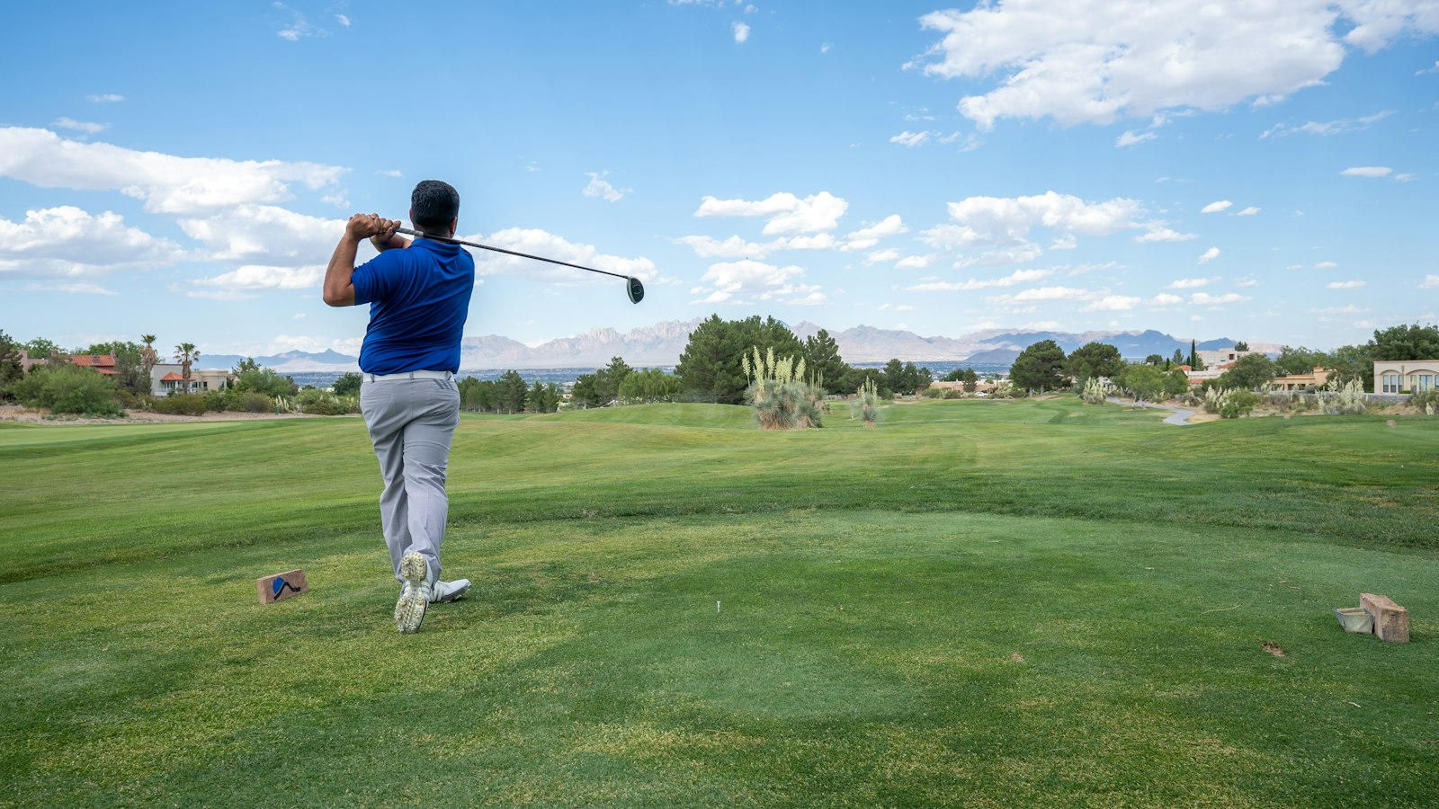 Golfeur en plein swing sur un fairway, ciel bleu